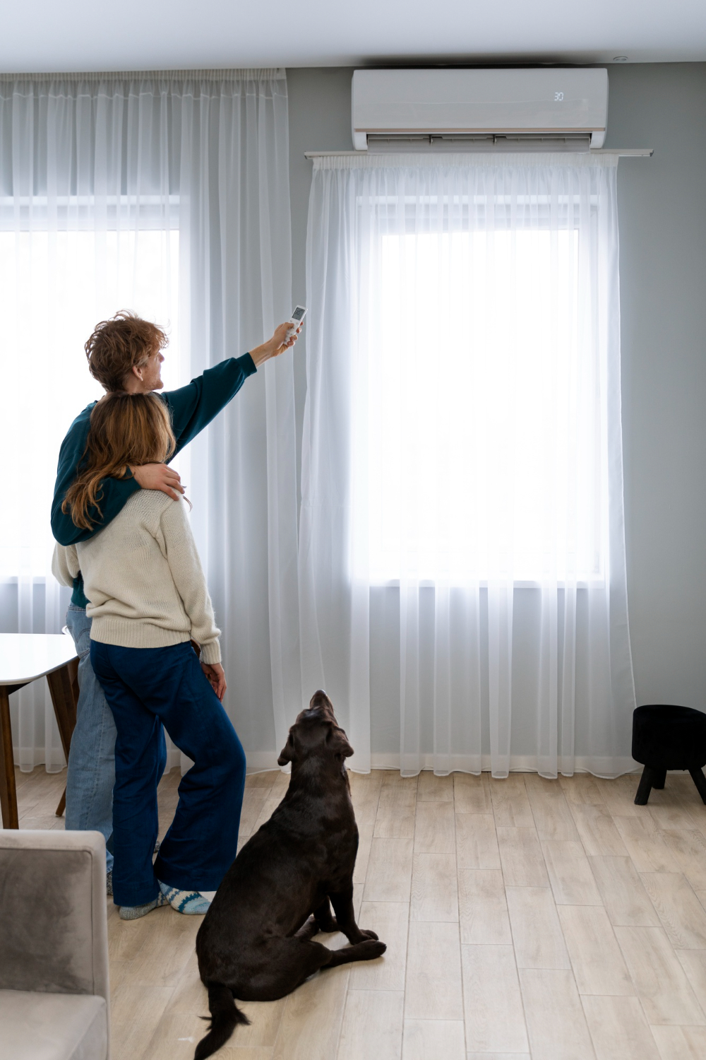 Couple détendu avec chien profitant d’une climatisation murale Plagnol dans un salon lumineux à Langon