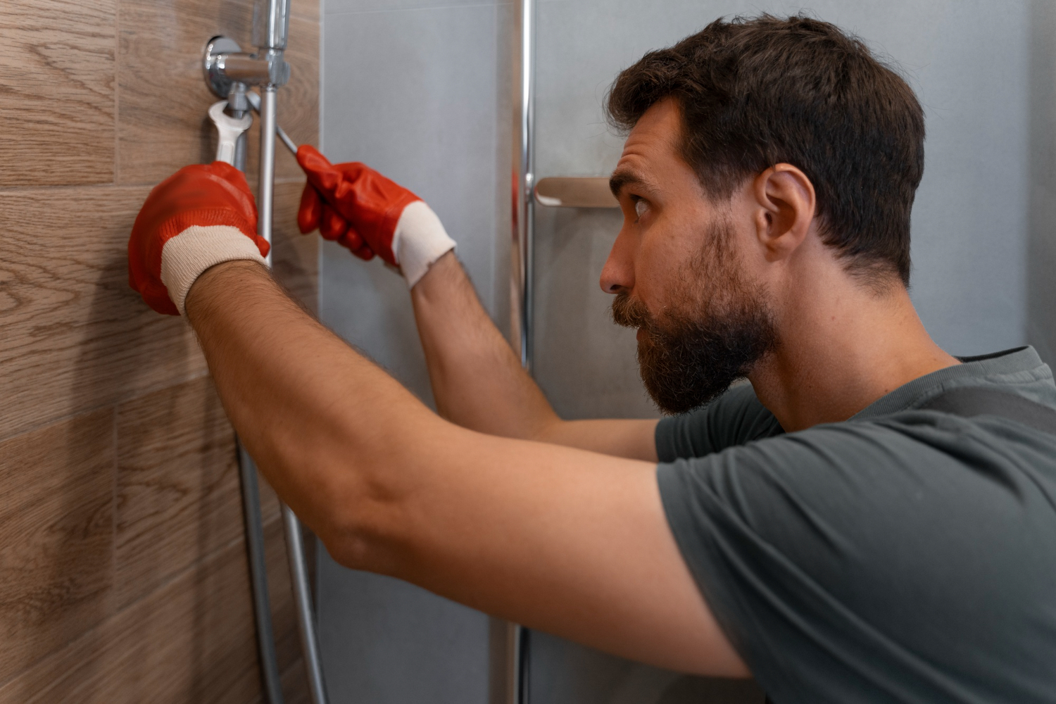 Plombier plagnol à langon réparant une douche moderne dans une salle de bain au carrelage effet bois